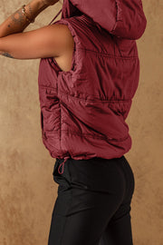 Burgundy quilted hooded puffer vest with adjustable drawcord hem and zip pocket.