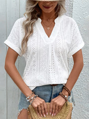White eyelet V-neck tunic with rolled sleeves and intricate patterns.