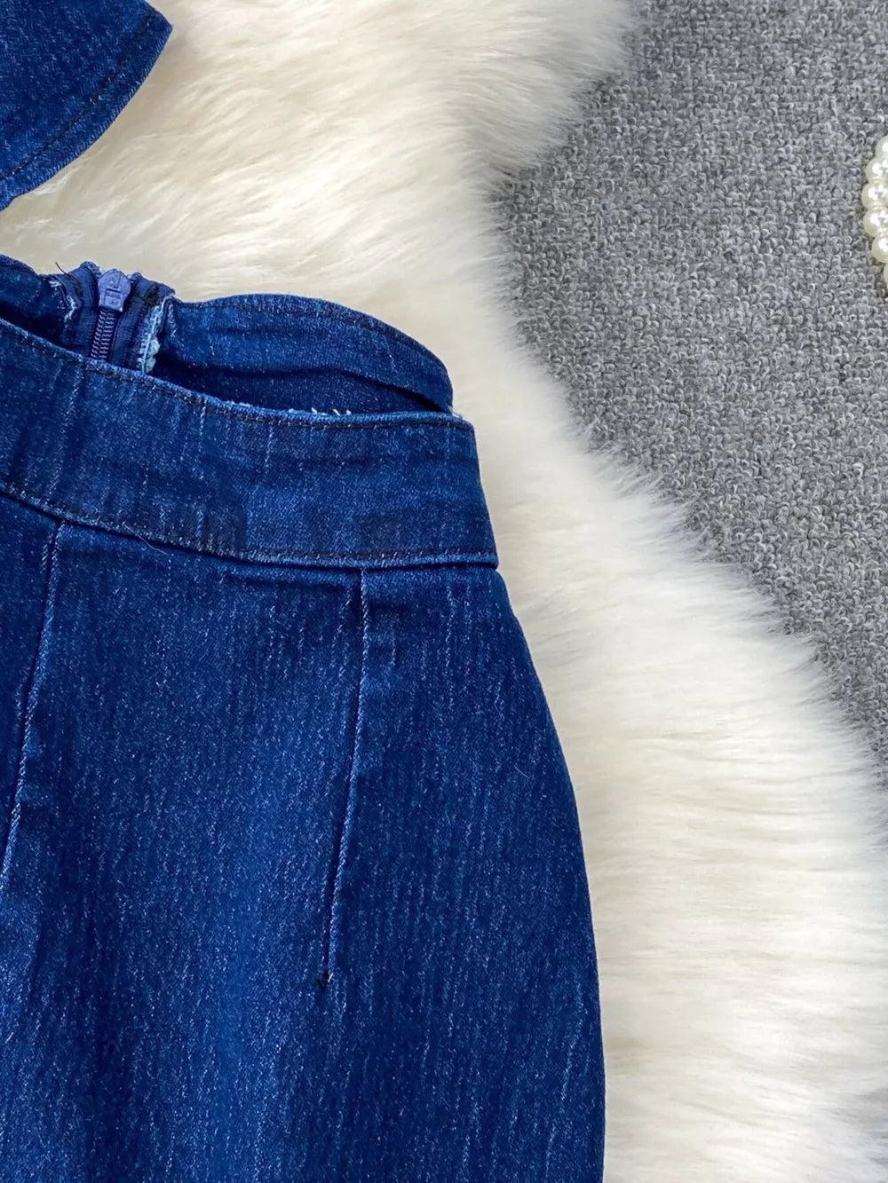 Dark blue cotton denim vest and flare jeans set with asymmetrical button detail and zipper closure.