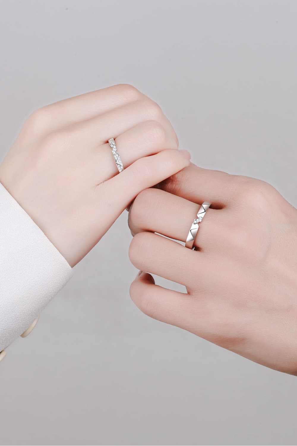 Geometric rhodium pavé ring set with diamond accents on two hands.