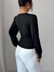 Black ruched V-neck blouse with pearl embellished cuffs and puff sleeves.