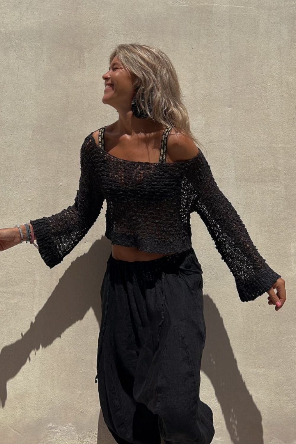 Black asymmetric crochet crop top with bell sleeves and a scoop neck.