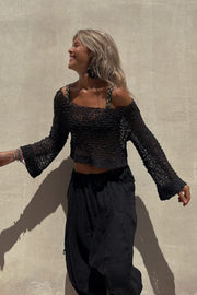 Black asymmetric crochet crop top with bell sleeves and a scoop neck.