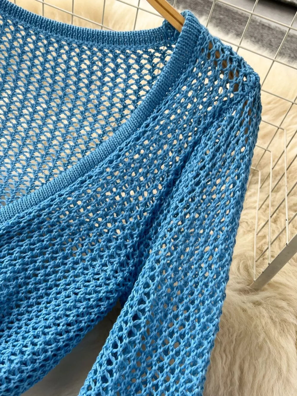 Blue crochet knit tied crop top with V-neck and long sleeves.