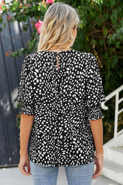 Black spot print blouse with shirred short sleeves and keyhole back detail.