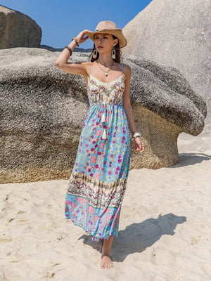 Maxi dress with floral border print, tassel detail, and spaghetti straps.