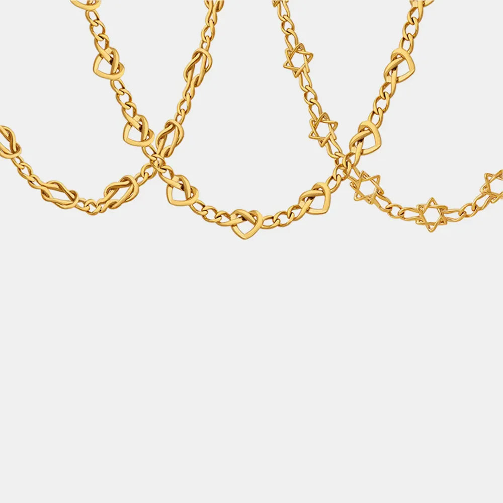 18K gold bracelet with heart and knot links, and star charms.