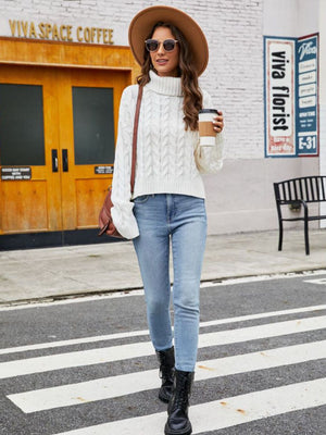 White cable-knit acrylic sweater with a high neck and long sleeves.