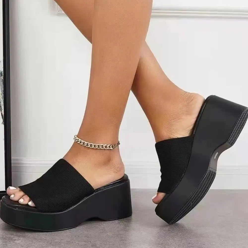 Black knit platform slide sandals with a chunky sole and chain anklet.