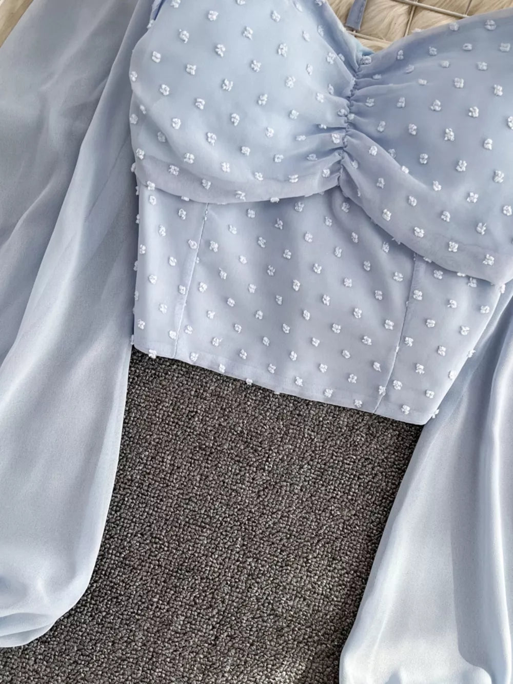 Blue Swiss dot maternity blouse with ruffled sweetheart neckline and sheer balloon sleeves.