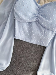 Blue Swiss dot maternity blouse with ruffled sweetheart neckline and sheer balloon sleeves.