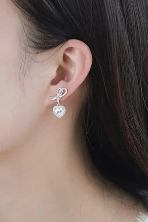 Silver bow-adorned heart moissanite drop earrings with pavé detailing.