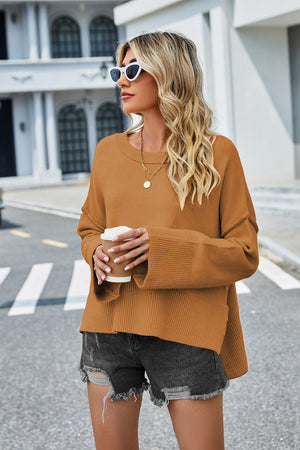 Caramel acrylic knit sweater with flared sleeves and slit hem detail.