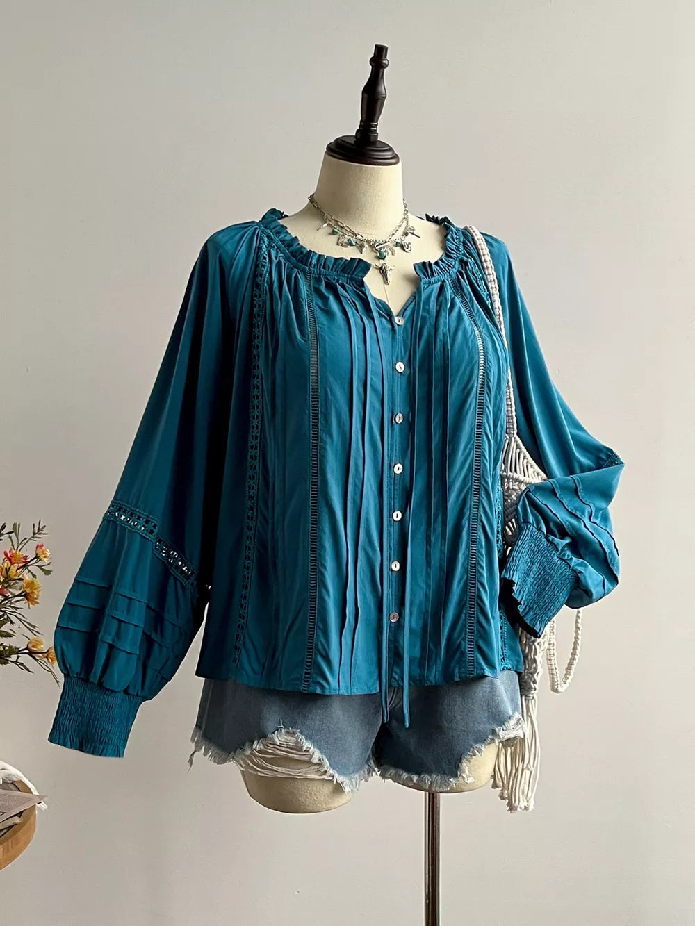 Teal ruffled lantern sleeve pleated blouse with cutout details and button front.