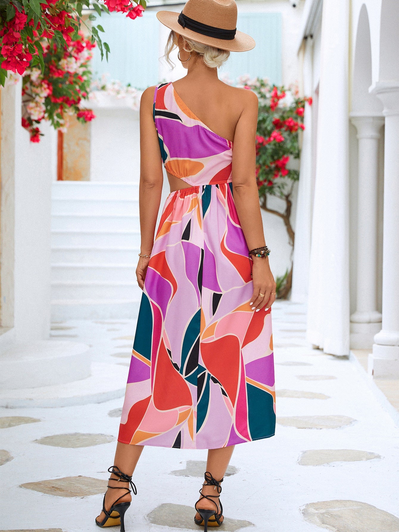 Abstract cutout midi dress with one-shoulder design and geometric print in magenta and blue tones.