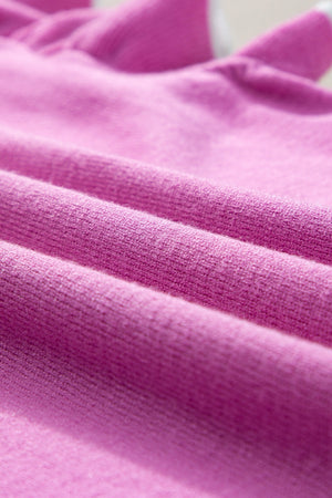 Fuchsia pink knit cardigan with ruffled sleeves and contrast trim detail.