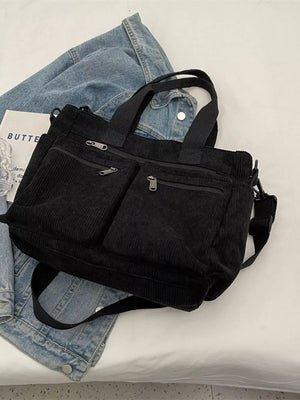 Black corduroy crossbody bag with multiple zippered pockets and adjustable strap.