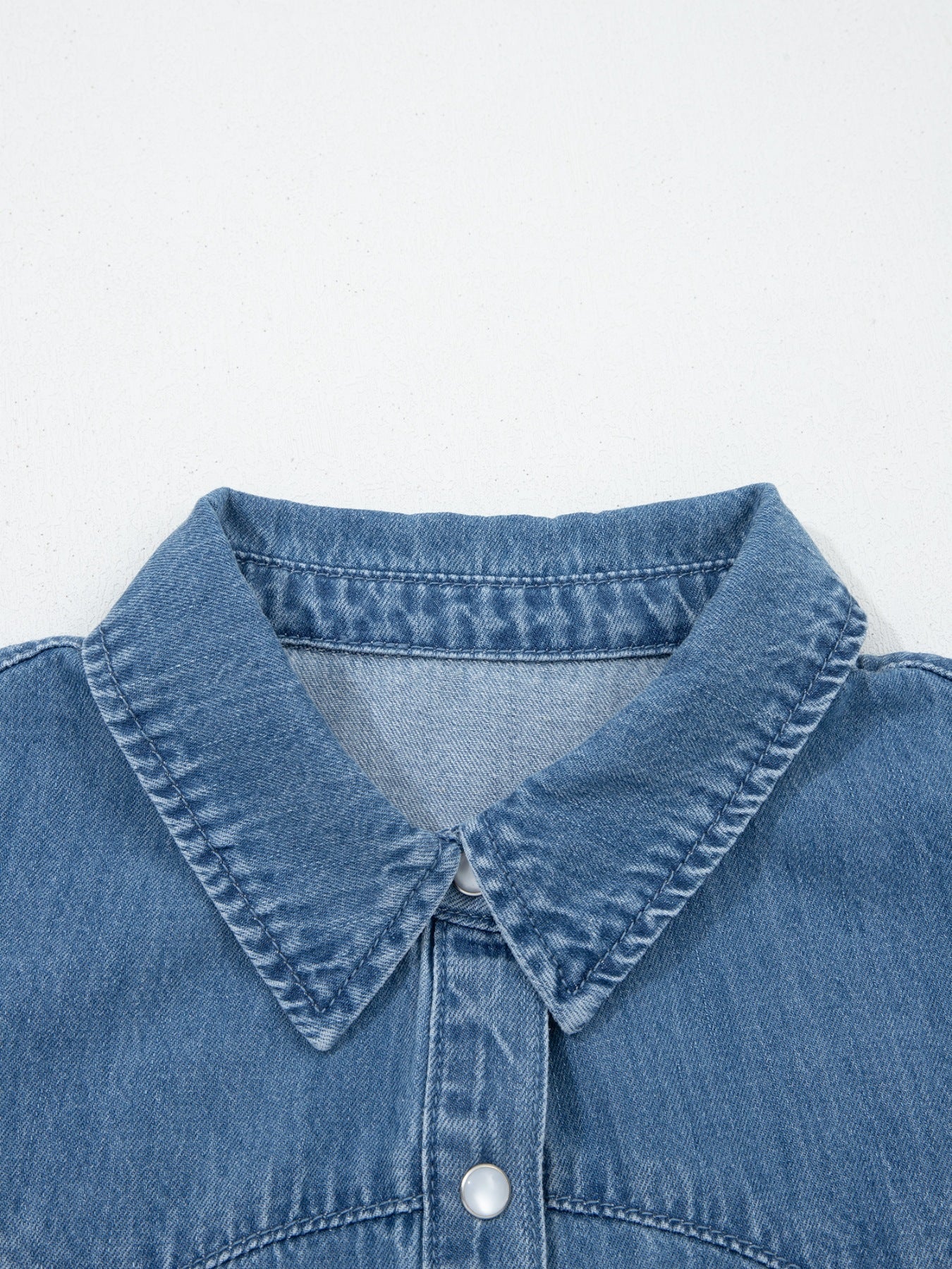 Ruffled denim button-up shirt with a classic collar and button closure.