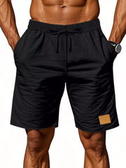 Black chino shorts with drawstring waist and tan patch detail.