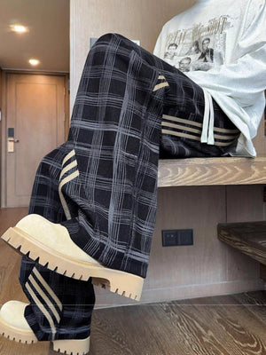 Men's black plaid wide leg sweatpants with side stripe detail and drawstring waist.