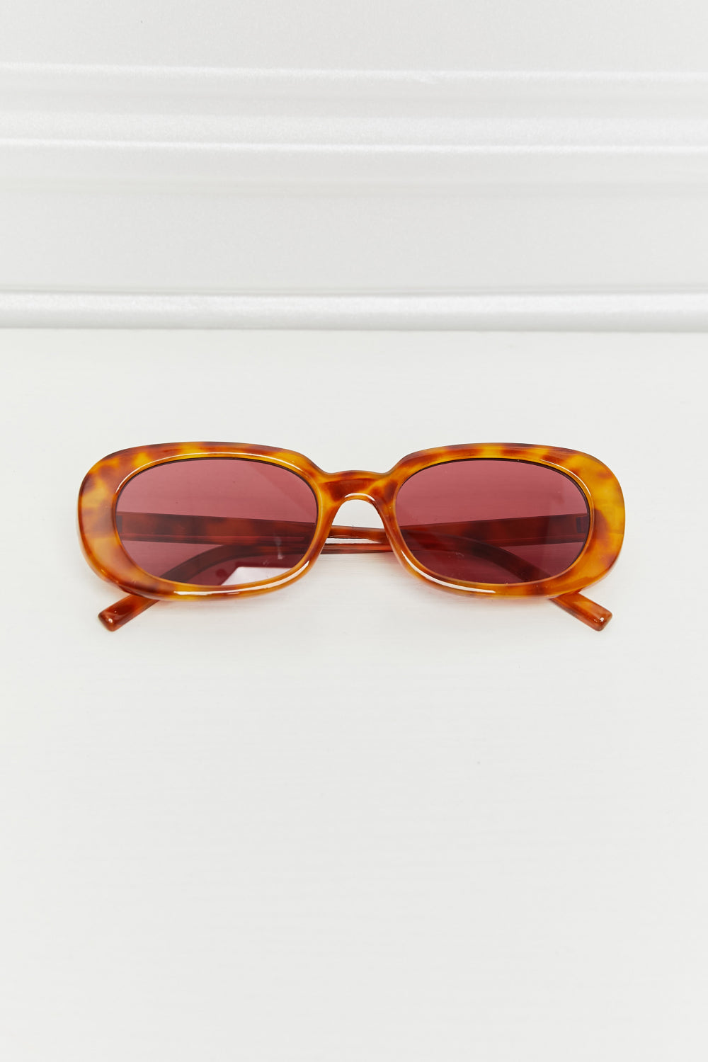 Tortoiseshell oval sunglasses with burgundy sunset lenses and a classic fit.