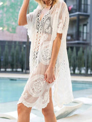 White lace cover-up with openwork detailing and short sleeves, worn over swimwear.