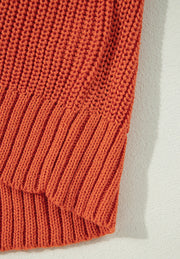 Orange acrylic knit sweater with ribbed texture and diagonal stitch detail.