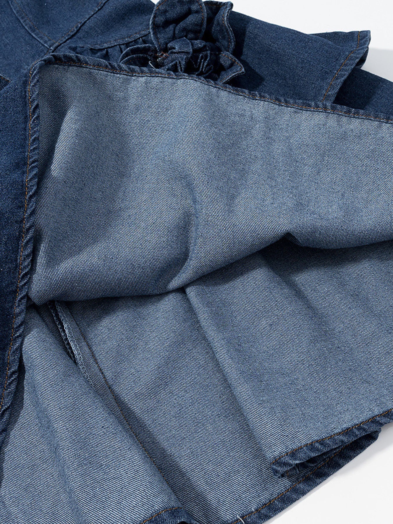 Denim mini dress with floral ruffle detail and frayed hem.