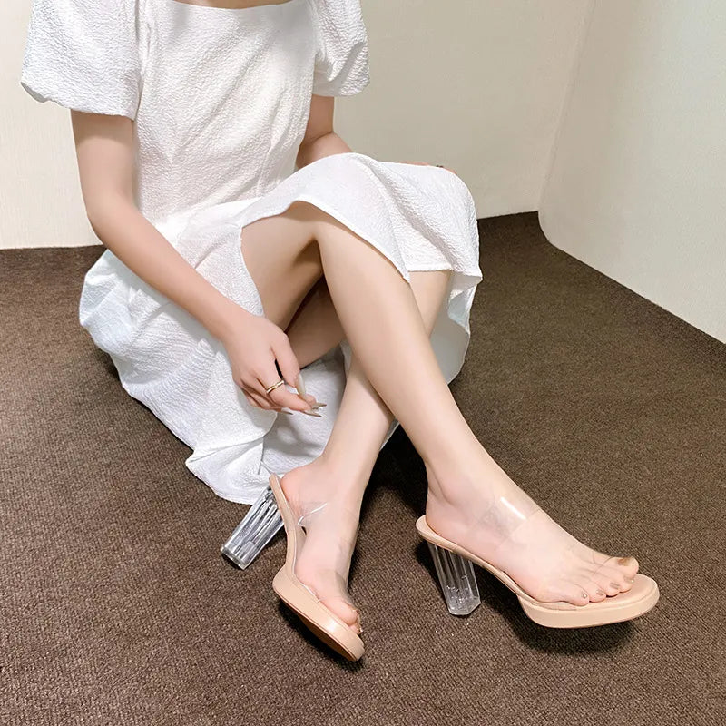 Lucite heel platform slides in beige with clear straps and a chunky block heel.