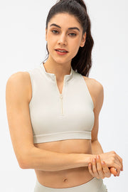 High-neck zip-front active crop top in light beige with sleeveless cut.