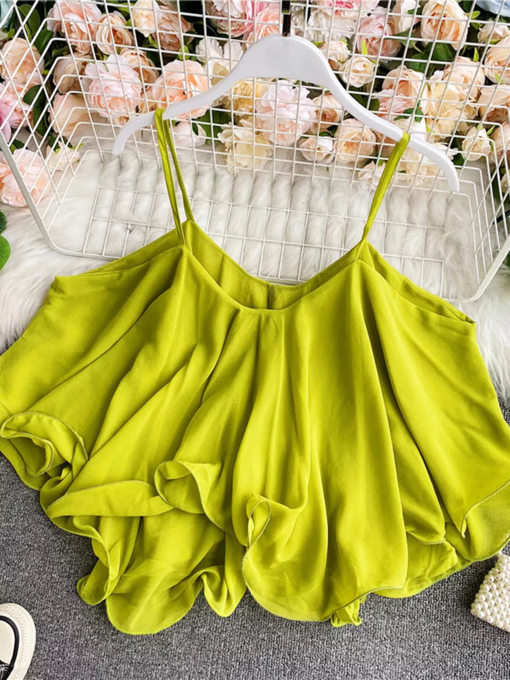 Light green camisole with spaghetti straps and ruffled hem detail.
