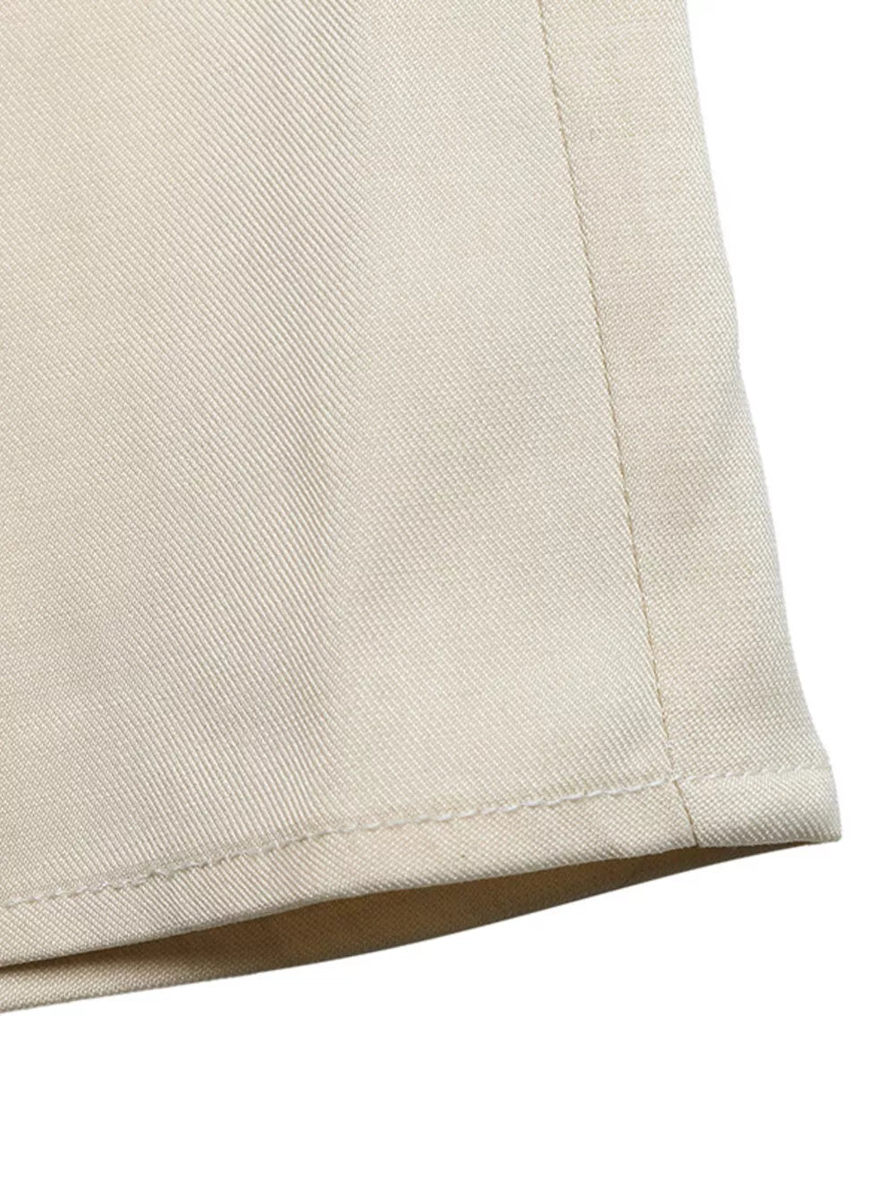 Elegant ruffled one-shoulder romper in beige, showing fabric texture and hem detail.