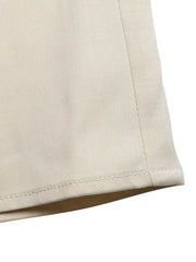 Elegant ruffled one-shoulder romper in beige, showing fabric texture and hem detail.