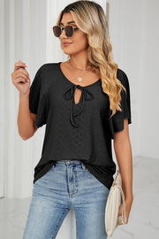 Black eyelet tie-neck blouse with flutter sleeves and a textured pattern.