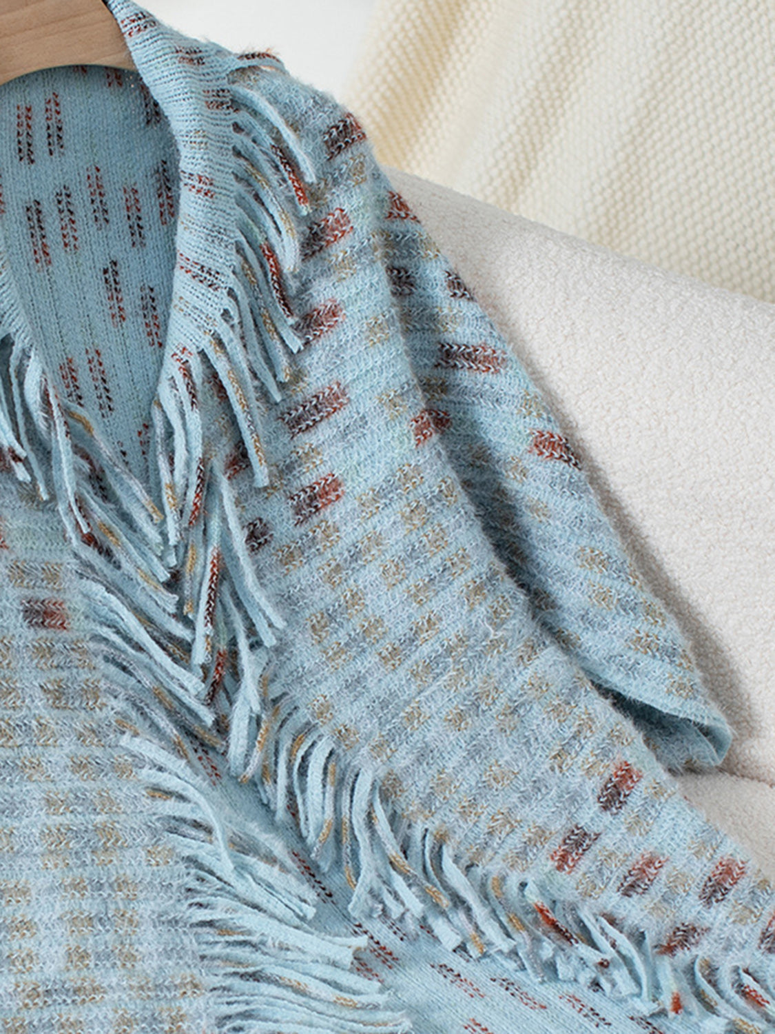 Light blue textured acrylic cardigan with fringe detail and woven pattern.