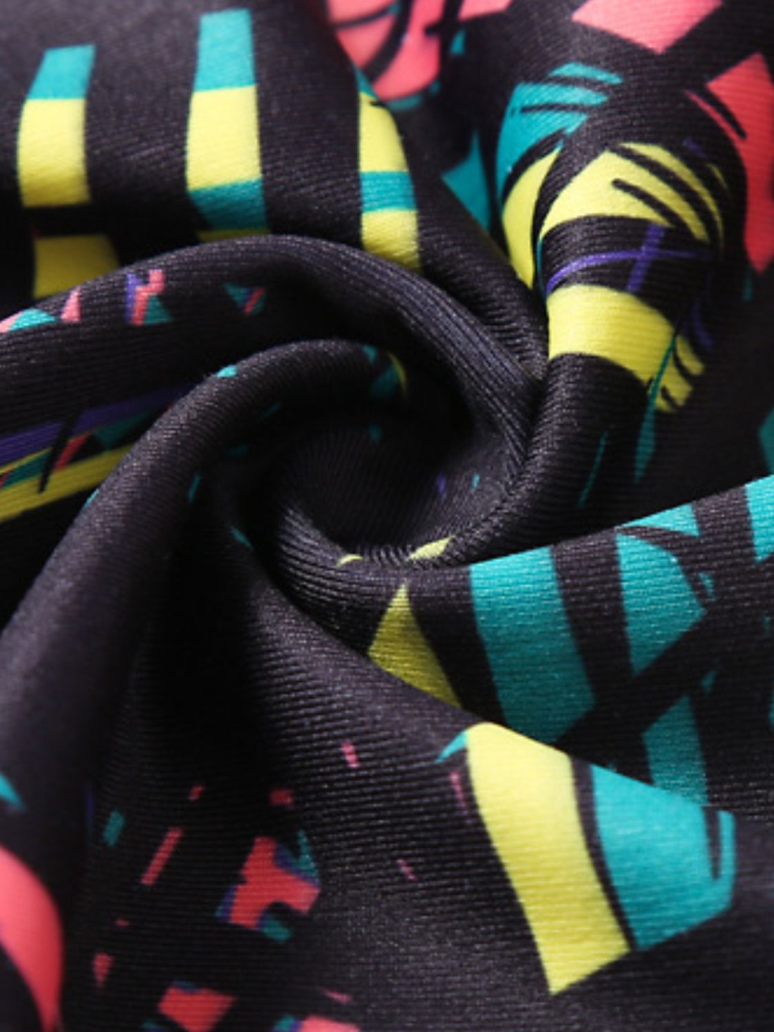 Black performance leggings with abstract geometric print in pink, yellow, and teal.