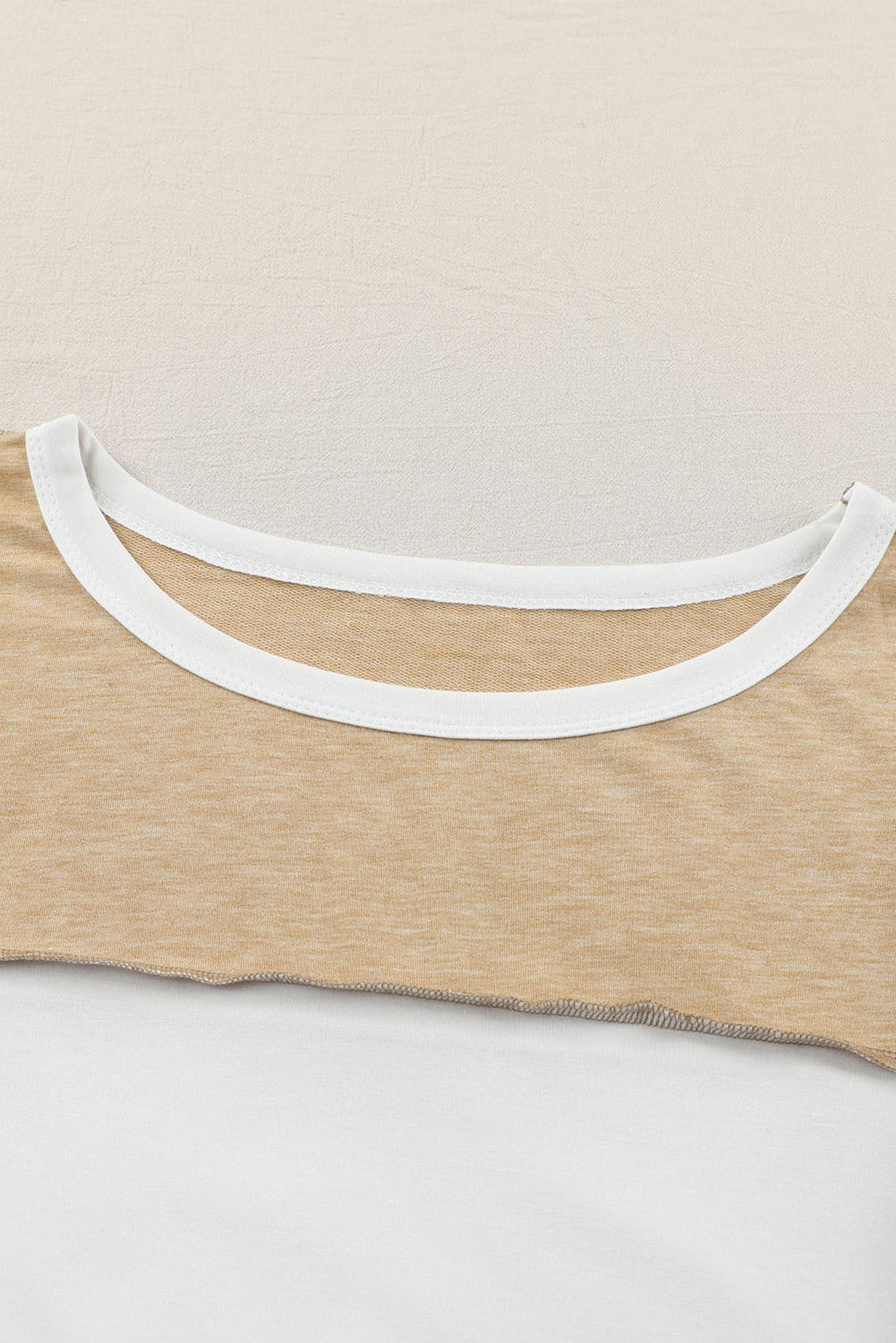 Colorblock knit top in tan with white contrast neckline and raw hem detail.