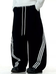 Men's black wide-leg sweatpants with white side stripes and drawstring waist.