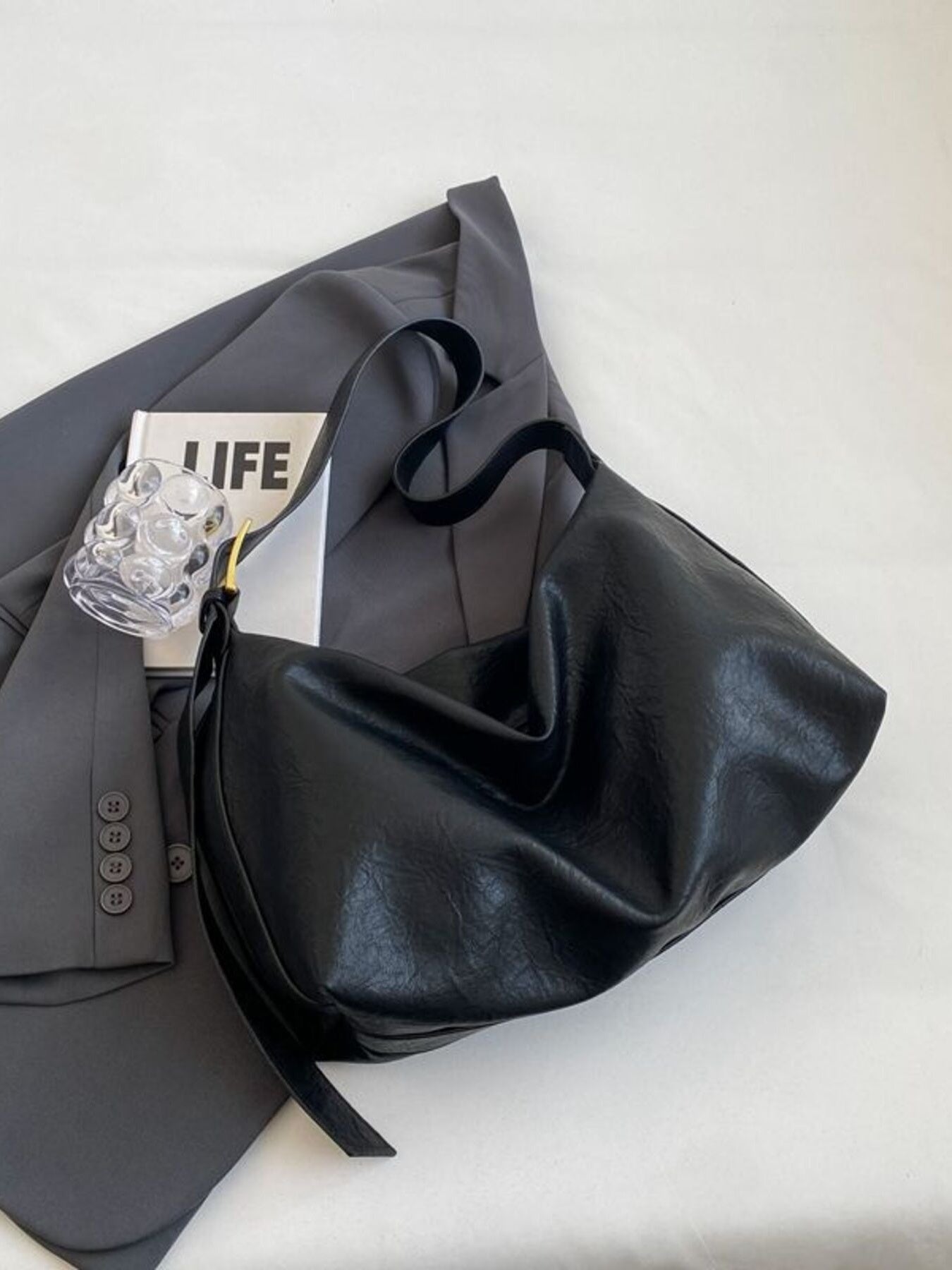 Black leather shoulder bag with adjustable strap and gold hardware detail