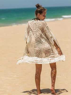 Apricot floral lace kimono cover-up with open front and short sleeves on a beach.