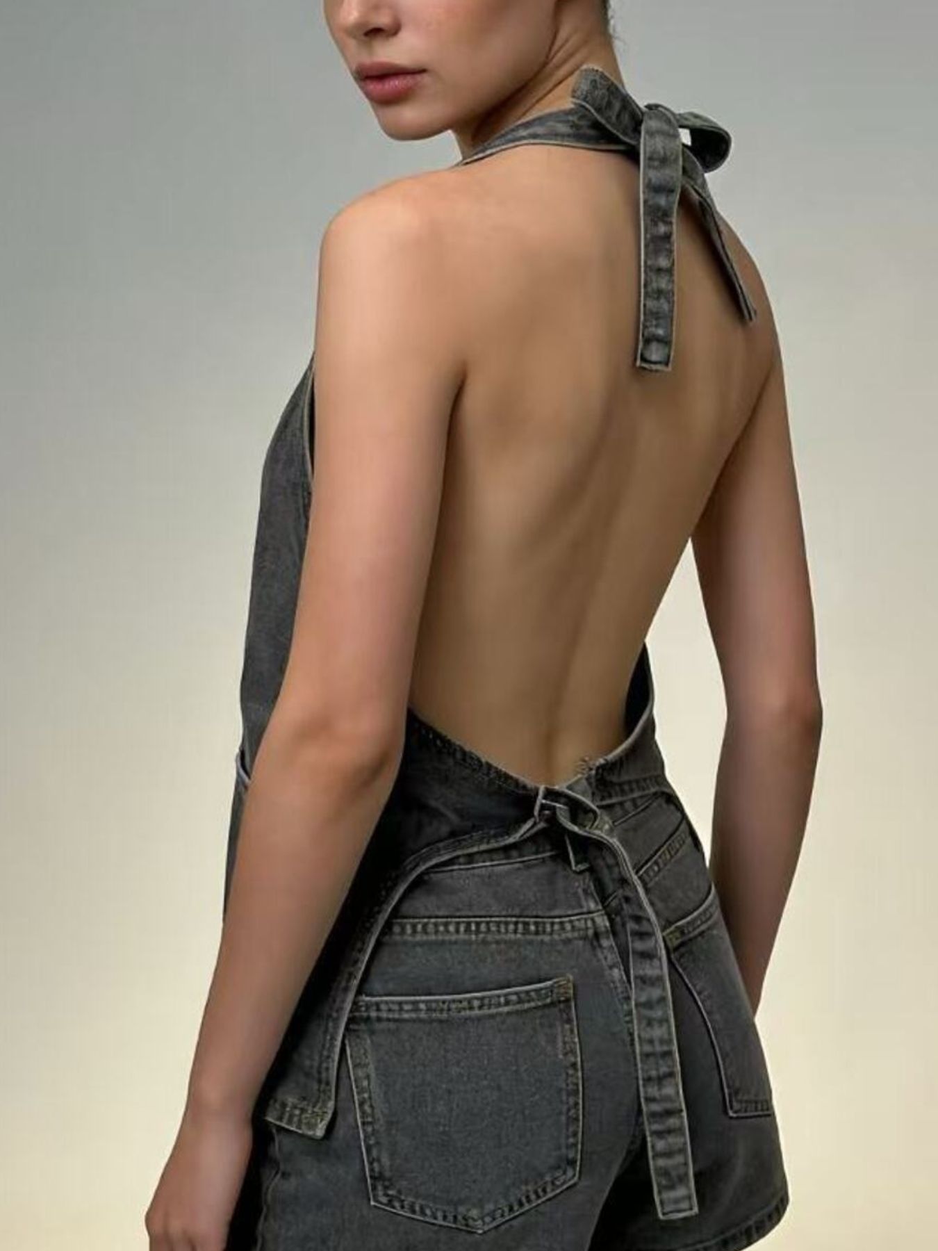 Button-down denim halter vest in gray with a tie back and open back detail.
