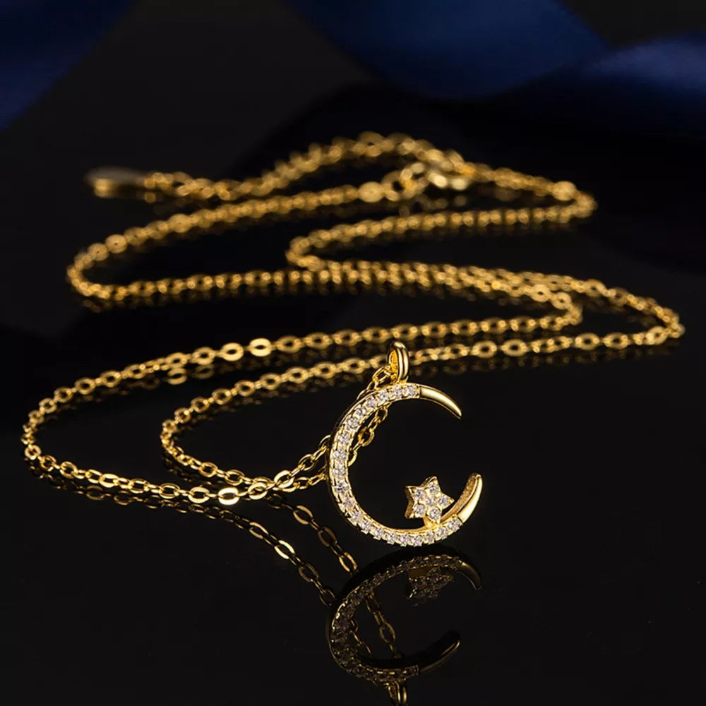 Gold crescent moon necklace with a star charm, encrusted with clear stones.
