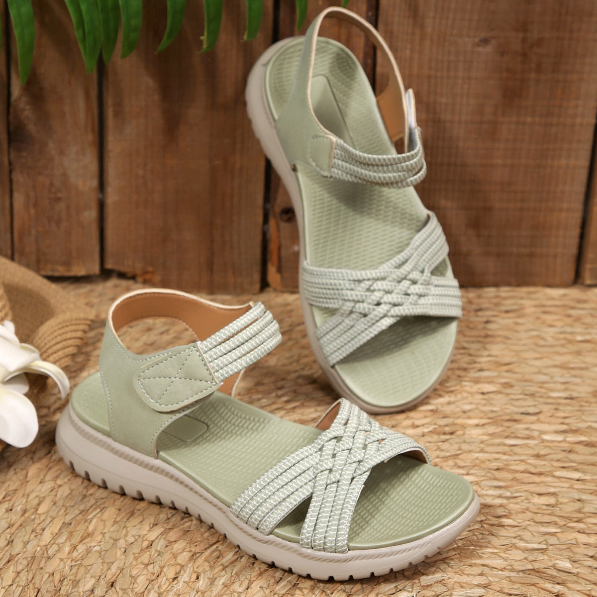 Green woven strap open-toe flat sandals with adjustable ankle strap.