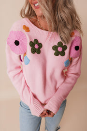 Pink knit sweater with embroidered floral appliqués and tassels.