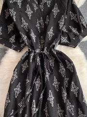 Black patterned drawstring jumpsuit with short puff sleeves and a tie waist.