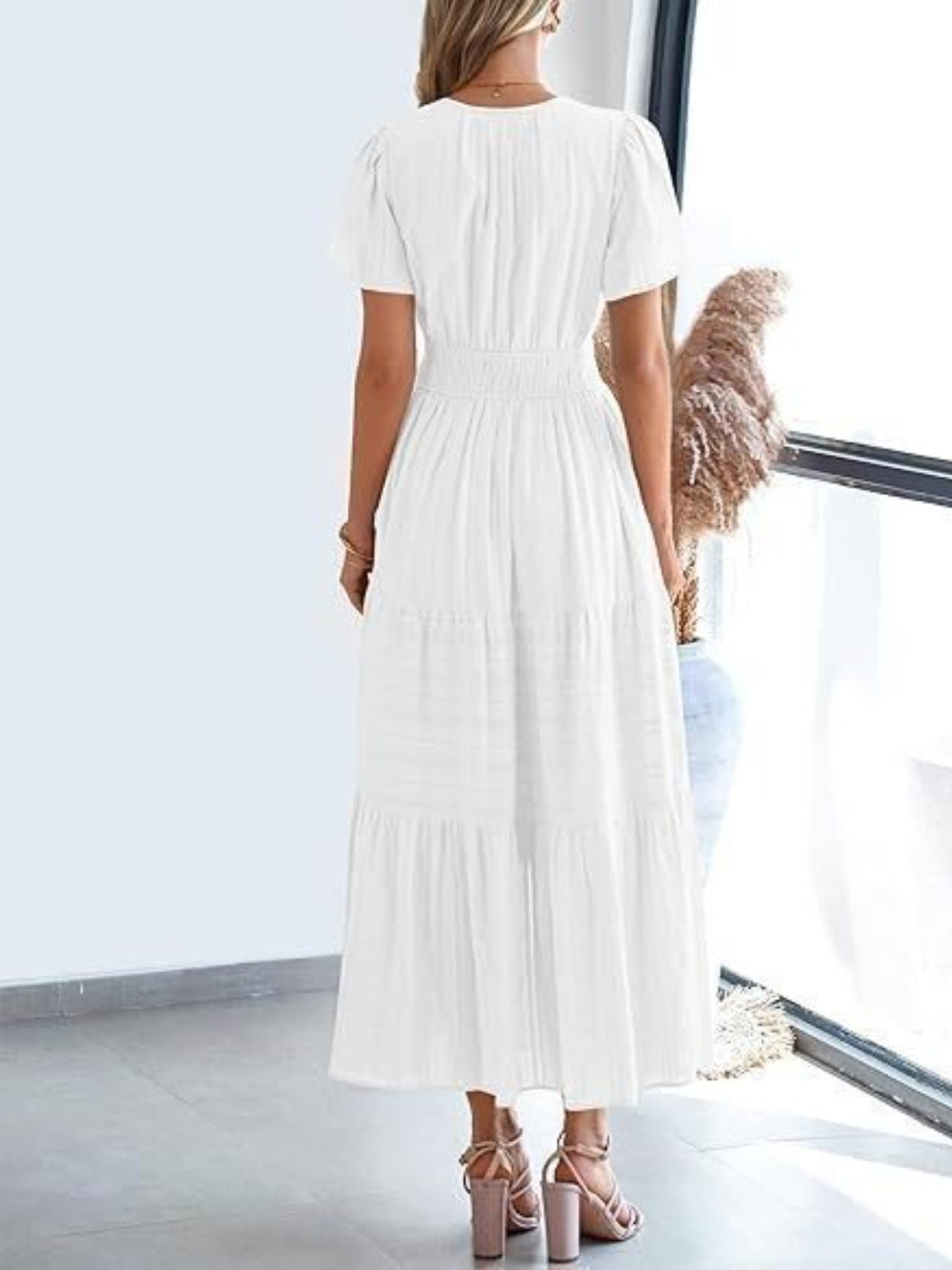 White V-neck tiered maxi dress with short sleeves and smocked waist, styled with sandals.
