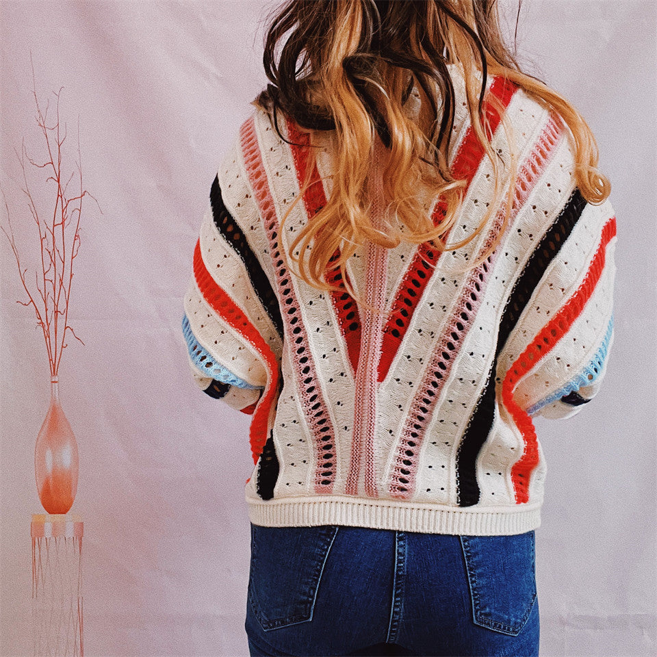 Colorblock openwork knit sweater with V-shaped stripes in red, black, pink, and blue.