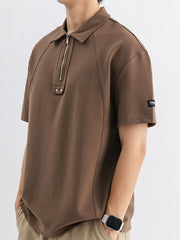 Brown cotton half-zip polo shirt with metallic zipper and accent buttons.