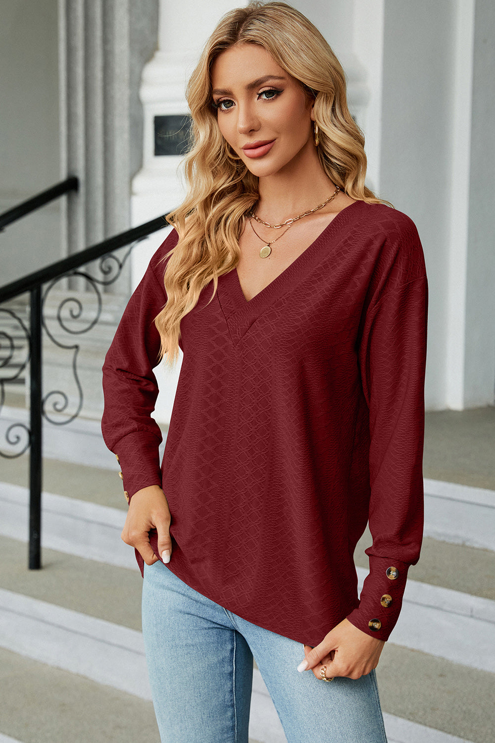 Burgundy diamond-textured V-neck blouse with button cuffs and long sleeves.