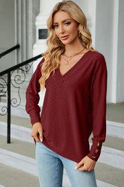 Burgundy diamond-textured V-neck blouse with button cuffs and long sleeves.